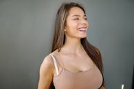 A charming young woman with long brunette hair smiling in a studio setting, exuding joy and elegance.